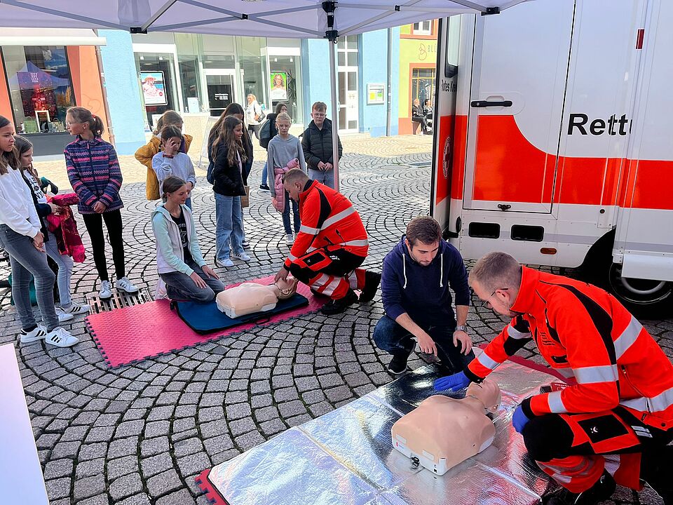 Ersthelfer des Roten Kreuzes führen einer Gruppe von Kindern vor, wie eine Reanimation funktioniert