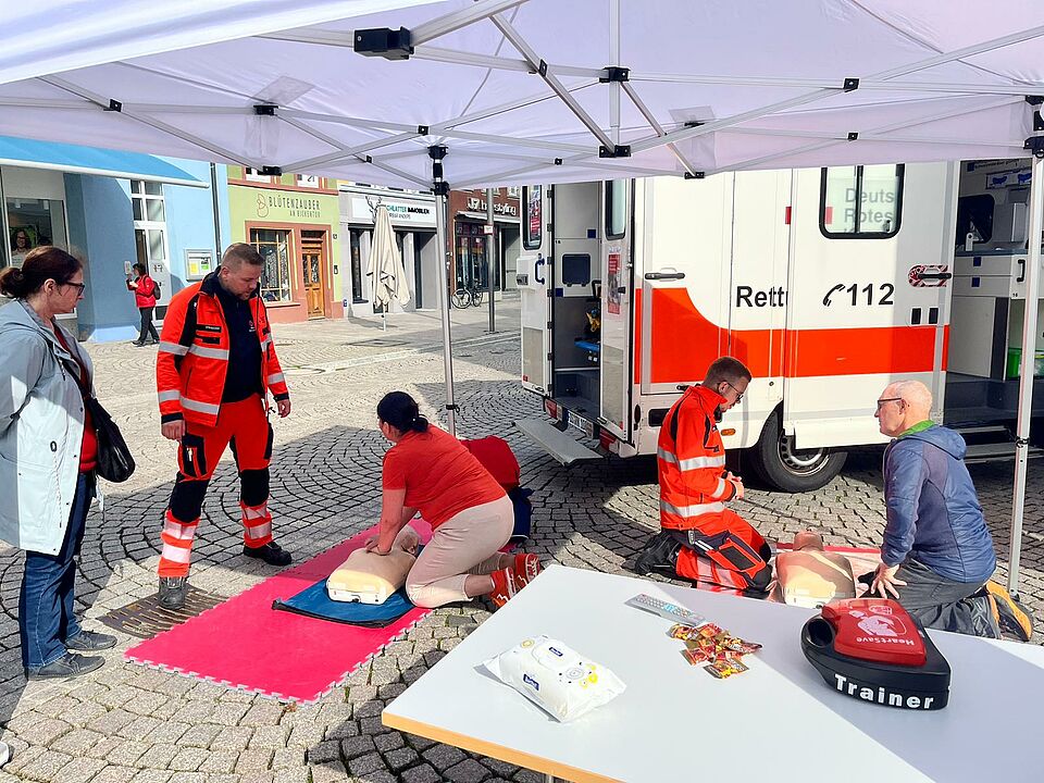 Passanten üben die Reanimation an einer Puppe